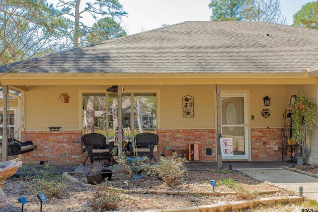 rear view of property featuring brick siding and a shingled roof