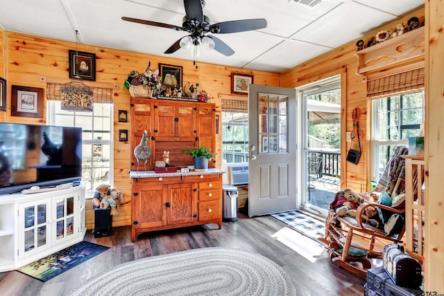 interior space with visible vents, wooden walls, wood finished floors, and a ceiling fan