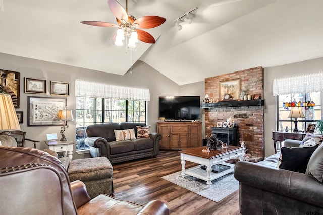 living area featuring a wood stove, dark wood-style flooring, ceiling fan, vaulted ceiling, and rail lighting