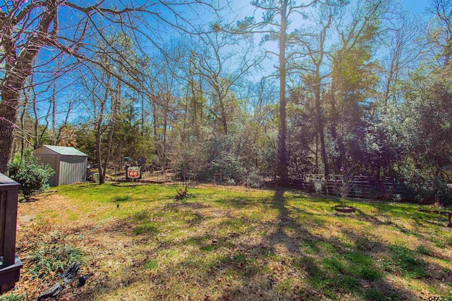 view of yard featuring an outbuilding, a storage unit, and fence