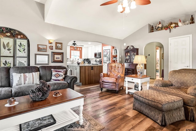 living room featuring ceiling fan, arched walkways, lofted ceiling, and wood finished floors