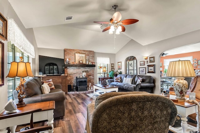 living room featuring visible vents, a wood stove, ceiling fan, vaulted ceiling, and dark wood-type flooring