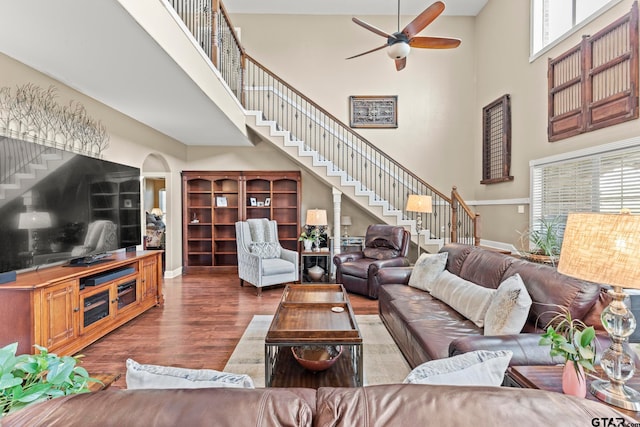 living room with dark wood-type flooring, a high ceiling, ceiling fan, and plenty of natural light