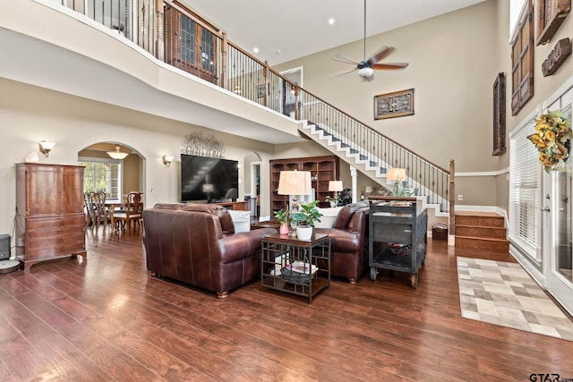 living room featuring a high ceiling, ceiling fan, and dark hardwood / wood-style flooring