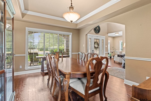 dining room with a raised ceiling, ornamental molding, and hardwood / wood-style flooring