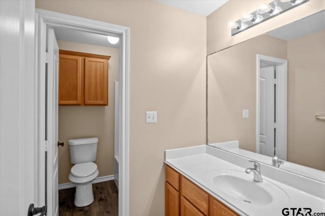 bathroom featuring a bath, vanity, hardwood / wood-style flooring, and toilet