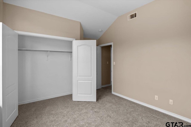 unfurnished bedroom with light carpet, a closet, and lofted ceiling