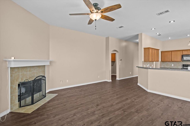 unfurnished living room featuring ceiling fan, a fireplace, and dark wood-type flooring