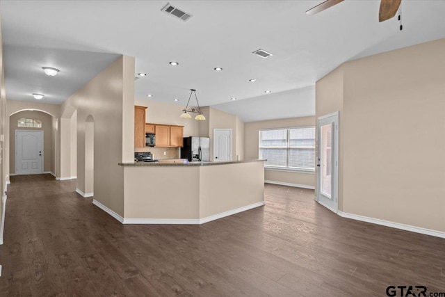 kitchen featuring hanging light fixtures, vaulted ceiling, dark hardwood / wood-style floors, stainless steel fridge, and light brown cabinetry