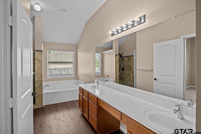 bathroom featuring hardwood / wood-style floors, vanity, separate shower and tub, and vaulted ceiling