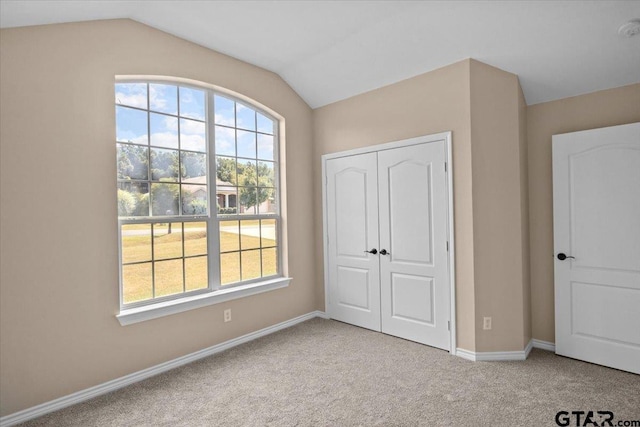 unfurnished bedroom with light carpet, a closet, and vaulted ceiling