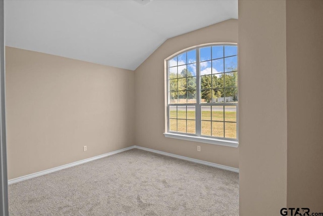 carpeted empty room with vaulted ceiling