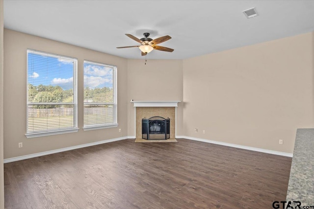 unfurnished living room with ceiling fan, dark wood-type flooring, and a tiled fireplace