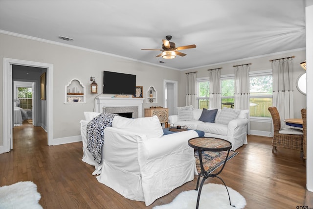 living area with ornamental molding, plenty of natural light, baseboards, and ceiling fan