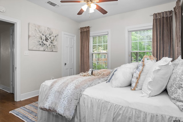 bedroom featuring baseboards, dark wood-style flooring, visible vents, and a ceiling fan