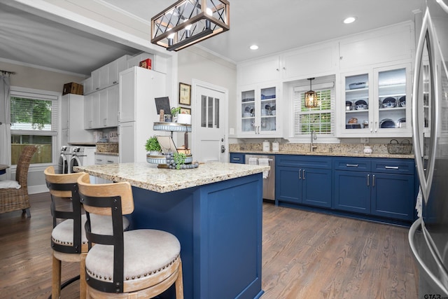 kitchen featuring stainless steel appliances, a breakfast bar, blue cabinets, ornamental molding, and washer and dryer