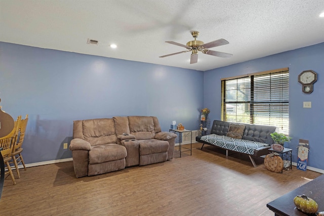 living room with ceiling fan, wood-type flooring, and a textured ceiling