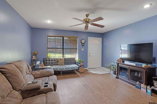 living room featuring a textured ceiling, ceiling fan, and light hardwood / wood-style flooring