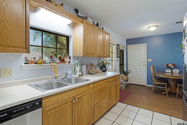 kitchen with a textured ceiling, light hardwood / wood-style floors, stainless steel dishwasher, and sink