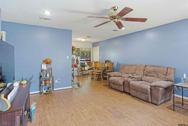 living room featuring a textured ceiling, light hardwood / wood-style flooring, and ceiling fan