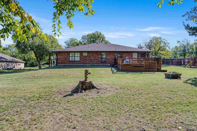 rear view of house with a lawn, a fire pit, and a wooden deck