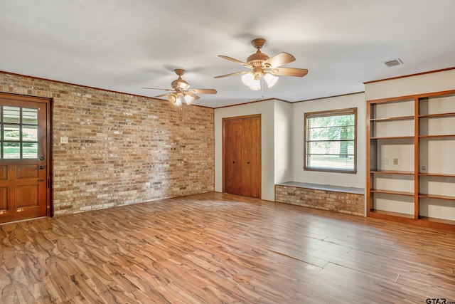 559 Elm St, Frankston, TX 75763 - unfurnished living room featuring brick wall, healthy amount of natural light, ceiling fan, and wood finished floors