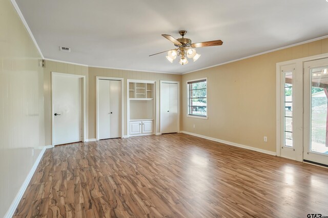 559 Elm St, Frankston, TX 75763 - unfurnished bedroom with crown molding, wood finished floors, baseboards, and two closets