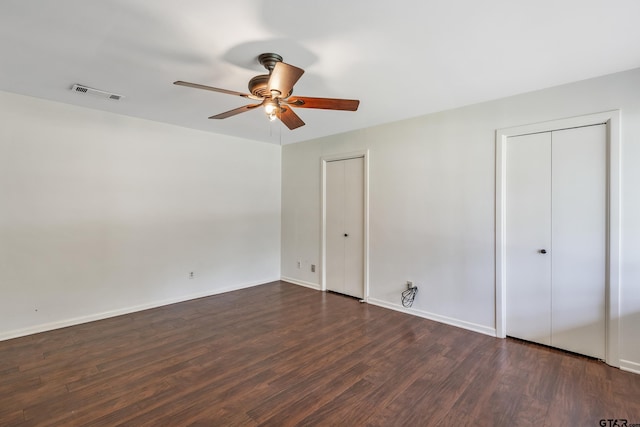 559 Elm St, Frankston, TX 75763 - unfurnished bedroom with dark wood finished floors, multiple closets, baseboards, and ceiling fan