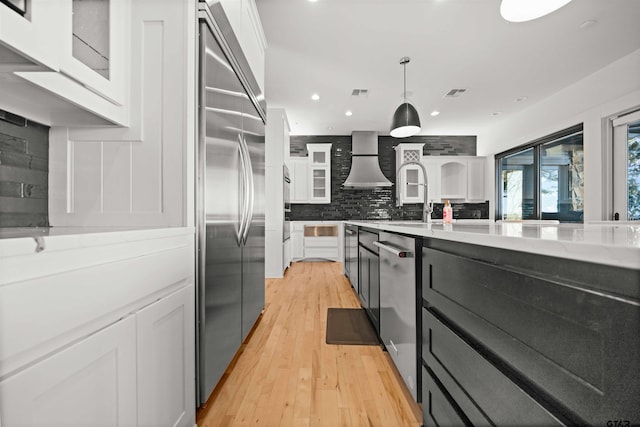 kitchen with glass insert cabinets, white cabinetry, stainless steel appliances, and decorative light fixtures