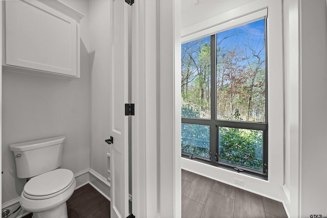 bathroom with toilet, baseboards, and wood finished floors