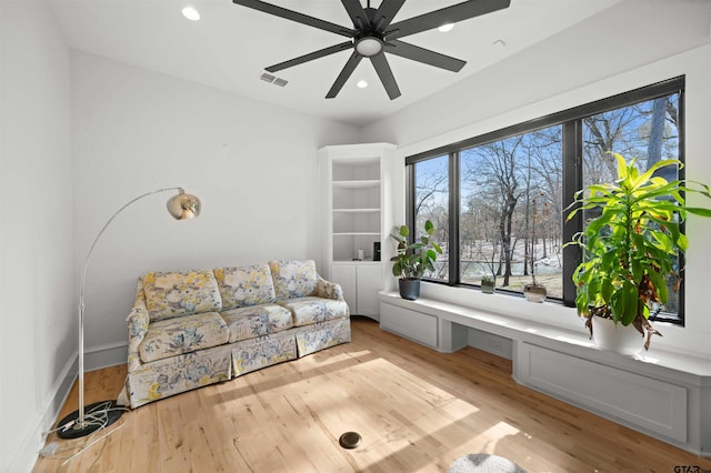 living area with light wood finished floors, recessed lighting, visible vents, built in study area, and ceiling fan