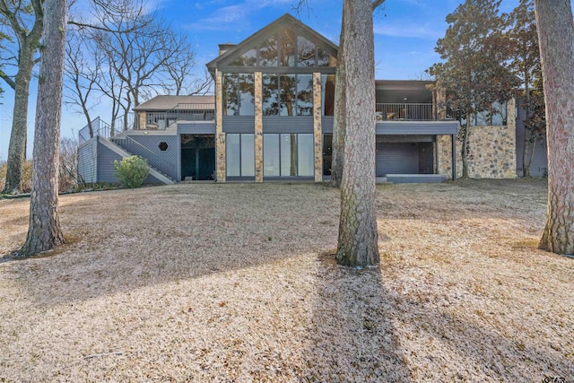 rear view of property featuring stone siding and a balcony