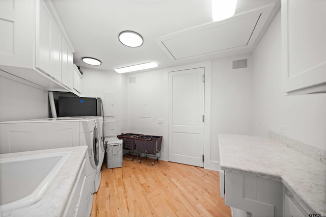 laundry room with a sink, light wood-style floors, washer and dryer, cabinet space, and attic access