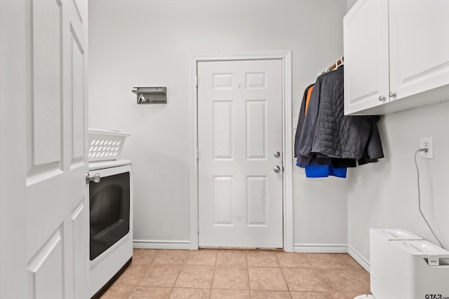 clothes washing area with light tile patterned floors, cabinet space, washer / clothes dryer, and baseboards