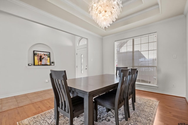 dining area featuring a chandelier, a raised ceiling, and wood finished floors