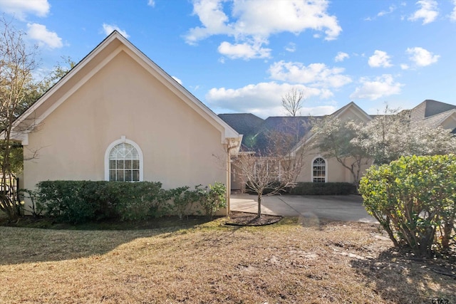 view of home's exterior with a patio, a yard, driveway, and stucco siding