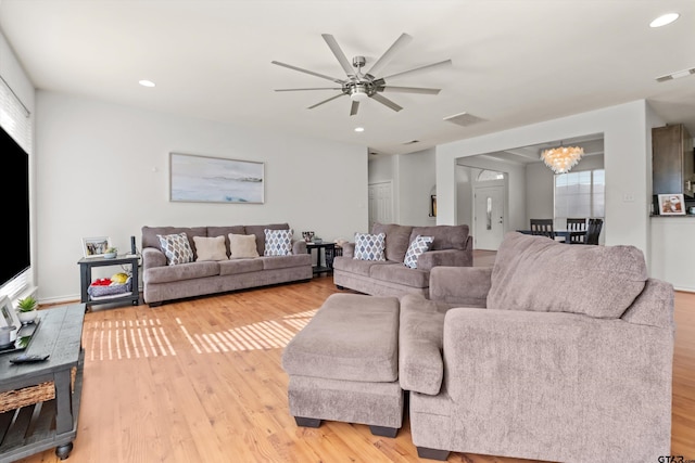 living room with recessed lighting, visible vents, light wood-style flooring, and ceiling fan with notable chandelier