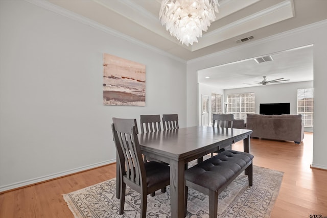 dining space featuring visible vents, light wood-style flooring, and a tray ceiling