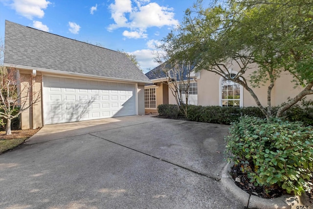 view of front of house with a garage, stucco siding, driveway, and roof with shingles