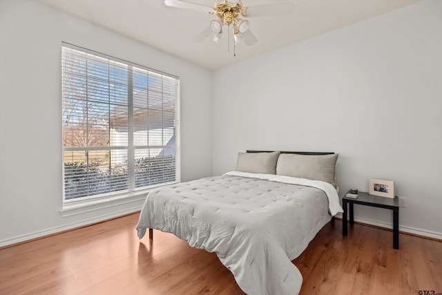 bedroom with a ceiling fan, wood finished floors, and baseboards