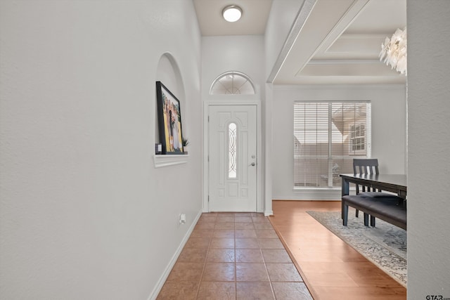 foyer with wood finished floors, baseboards, and ornamental molding