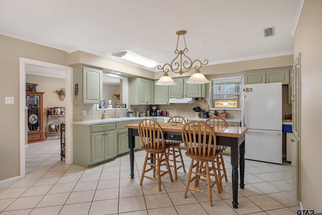 311 E Amherst St, Tyler, TX 75703 - kitchen featuring freestanding refrigerator, green cabinetry, ornamental molding, light countertops, and under cabinet range hood