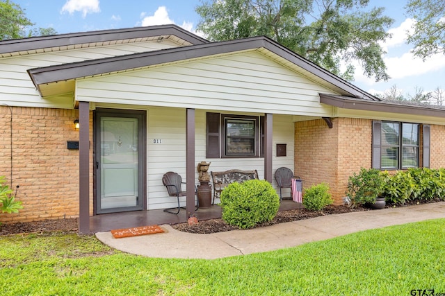311 E Amherst St, Tyler, TX 75703 - view of front facade with covered porch, a front lawn, and brick siding