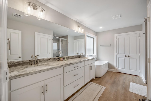 19128 Ambrosia Dr, Flint, TX 75762 - bathroom featuring a stall shower, double vanity, wood finished floors, a soaking tub, and baseboards
