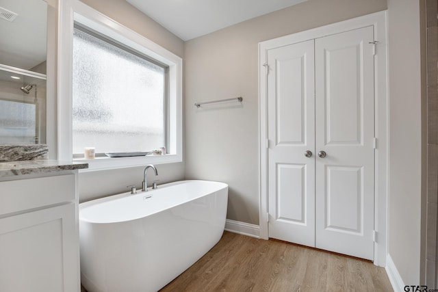 19128 Ambrosia Dr, Flint, TX 75762 - bathroom featuring wood finished floors, a stall shower, a freestanding tub, baseboards, and vanity