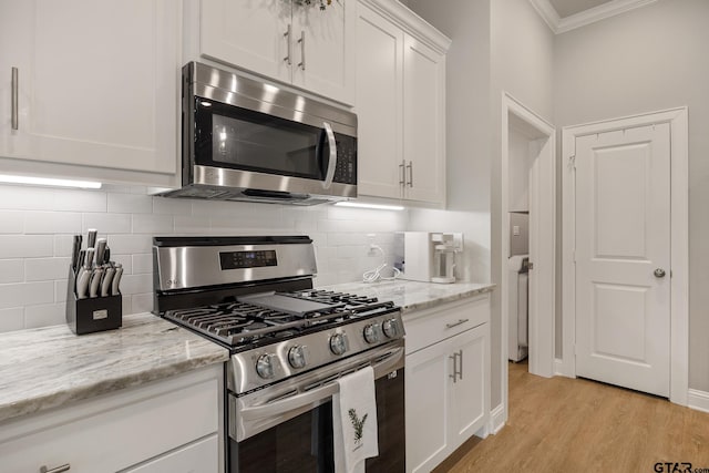 19128 Ambrosia Dr, Flint, TX 75762 - kitchen with appliances with stainless steel finishes, ornamental molding, white cabinetry, tasteful backsplash, and light wood-style flooring