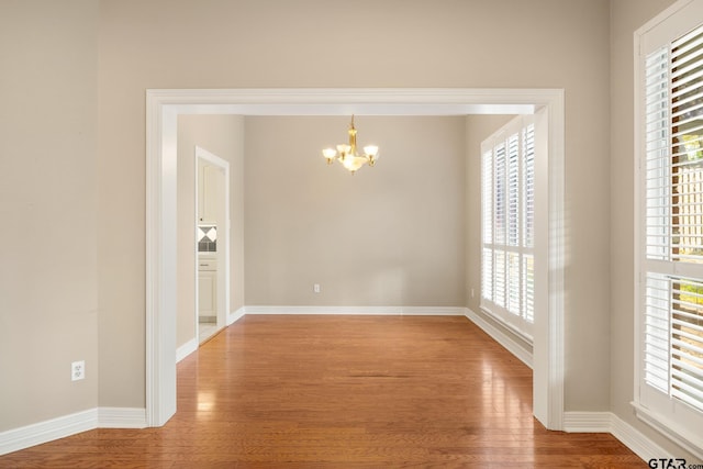 unfurnished dining area with a chandelier, hardwood / wood-style floors, and a healthy amount of sunlight