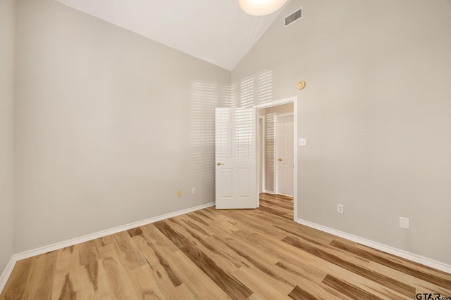 empty room with light hardwood / wood-style flooring and high vaulted ceiling