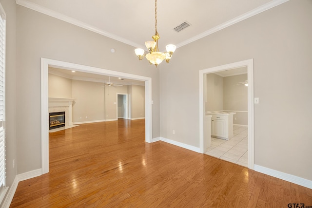 unfurnished dining area with ceiling fan with notable chandelier, light hardwood / wood-style flooring, and crown molding