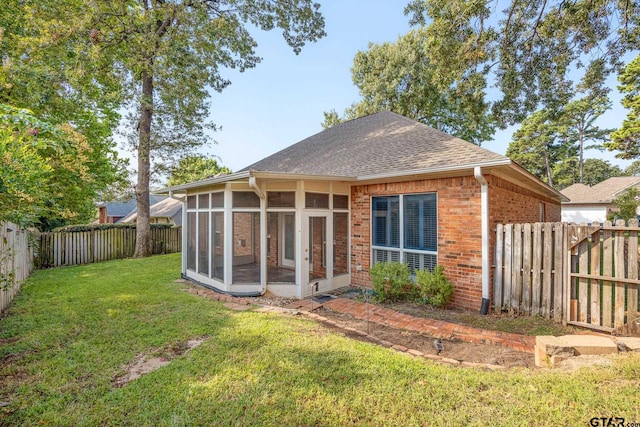 back of property featuring a lawn and a sunroom